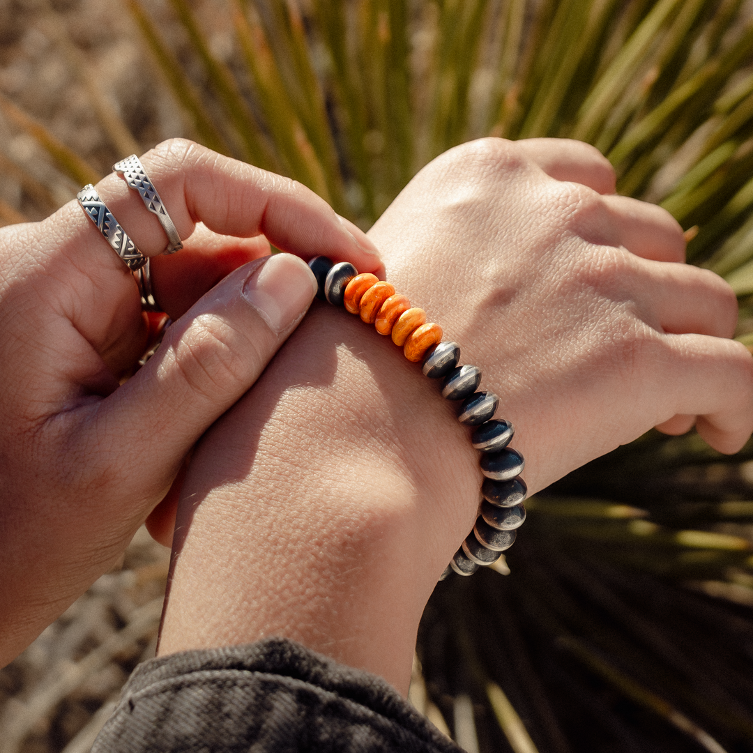 Bead Maiden: Spiny Oyster Stretch Bracelets featuring vibrant orange and dark beads, worn on a wrist.