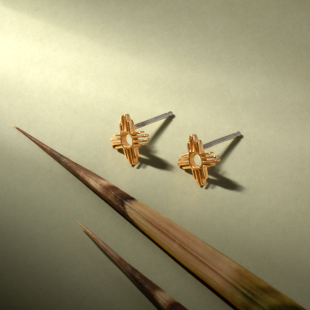 Enchantment Mini Zia Stud Earrings in sterling silver, featuring a Native American-inspired design, set against a soft green background.