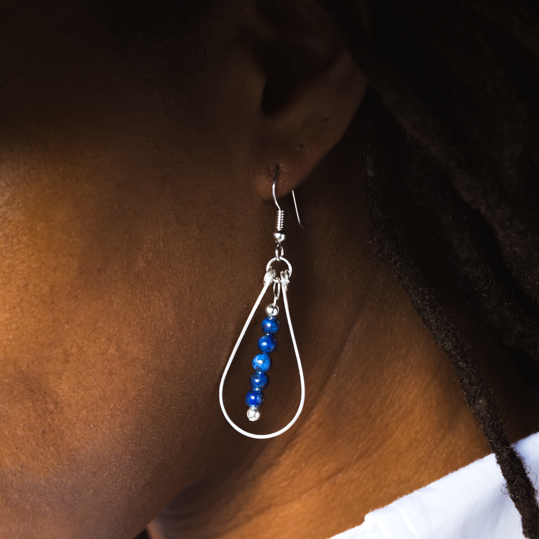 Bead Maiden: Wrapped Intention Earrings in sterling silver with blue beads, worn on a model's ear.