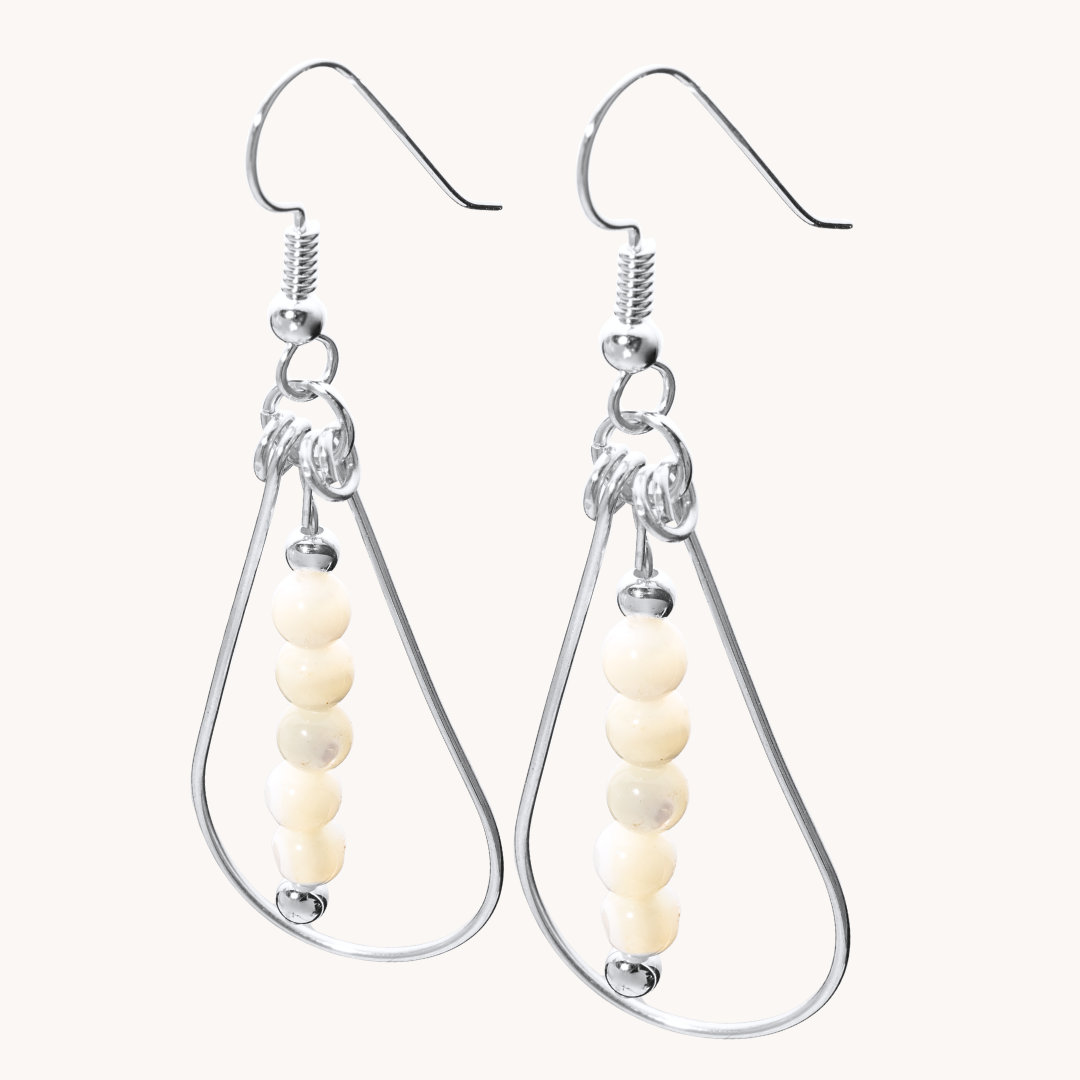 Bead Maiden: Wrapped Intention Earrings made of sterling silver with cream-colored beads, showcasing a teardrop design.
