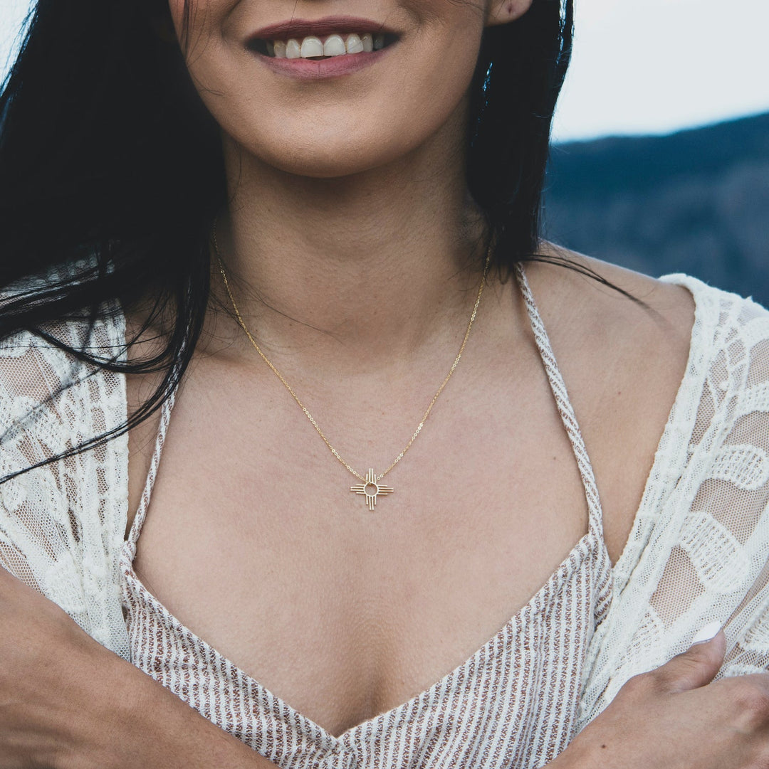 Enchantment: Petite Pendant & Zia Studs in sterling silver, worn by a woman with a warm smile, showcasing Native American-inspired design.