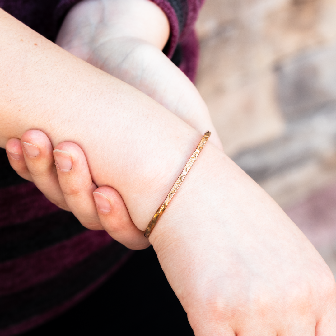 Sage Twist Stacker Bracelet by T.Skies, made of sterling silver, worn on a wrist with a textured design.