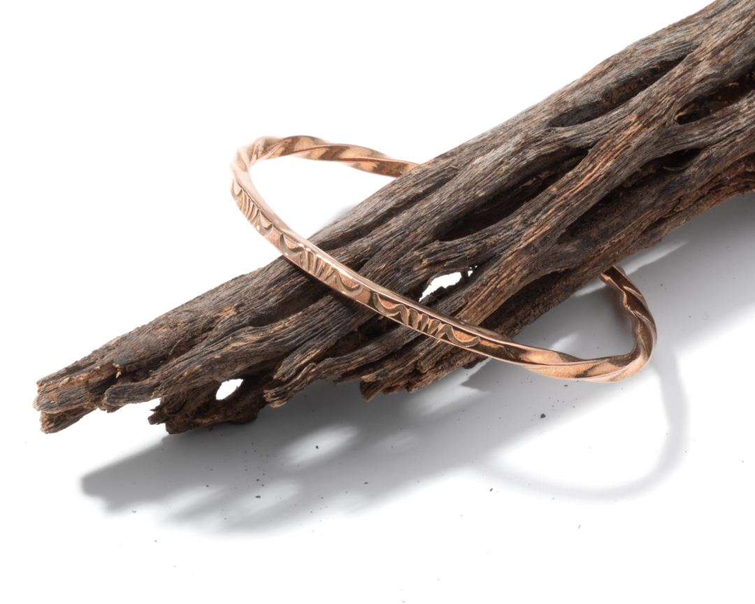Stamp Dancer: Sage Twist Stacker Bracelet, a twisted sterling silver bracelet resting on a piece of driftwood.