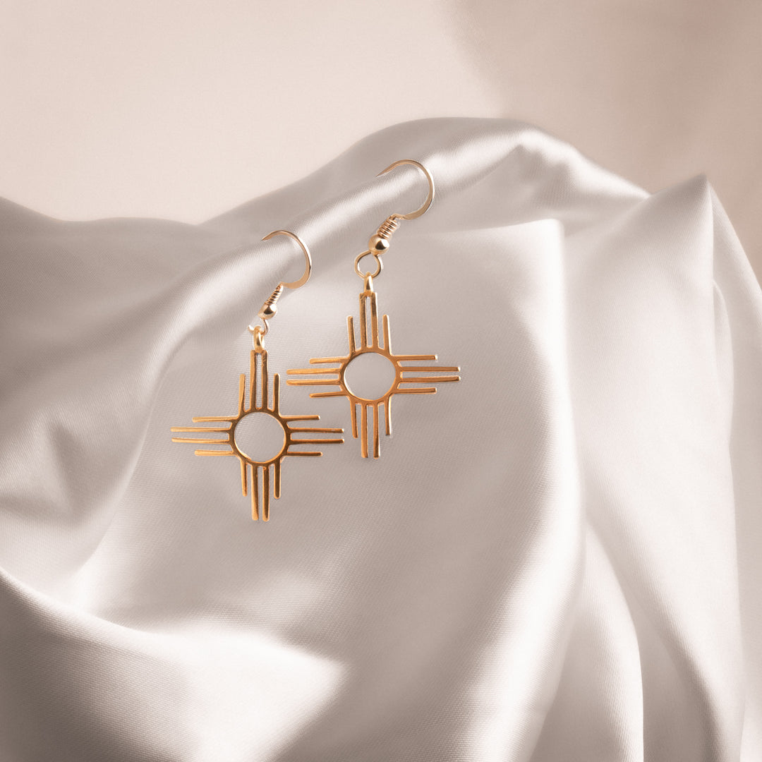 Enchantment: Zia Dangle Earrings made of sterling silver, featuring a geometric Zia sun symbol design.