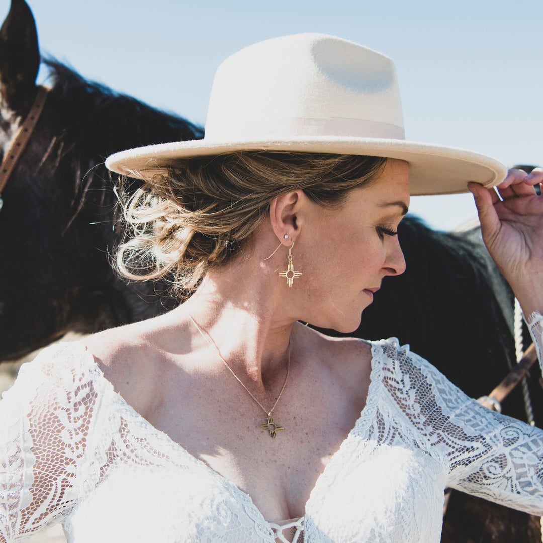 Enchantment: Zia Dangle Jewelry Set, sterling silver, worn by a woman in a lace top and hat, with a horse in the background.