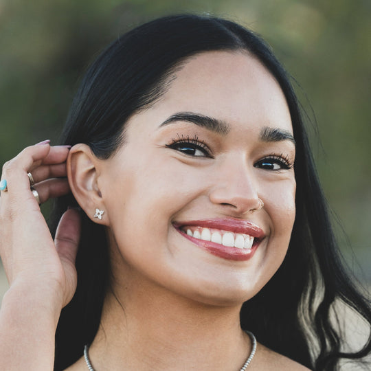 Enchantment: Sunrise Zia Stud Earring Trio in sterling silver, worn by a smiling woman with long dark hair.