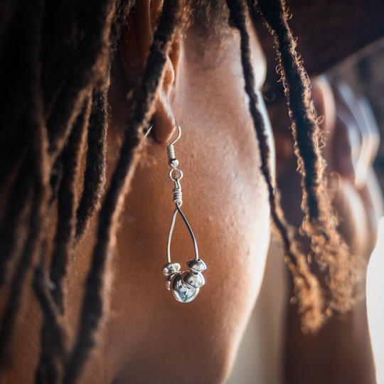 Desert Blossom: Lotus Flower Earrings in sterling silver, elegantly hanging from a model's ear with textured hair.
