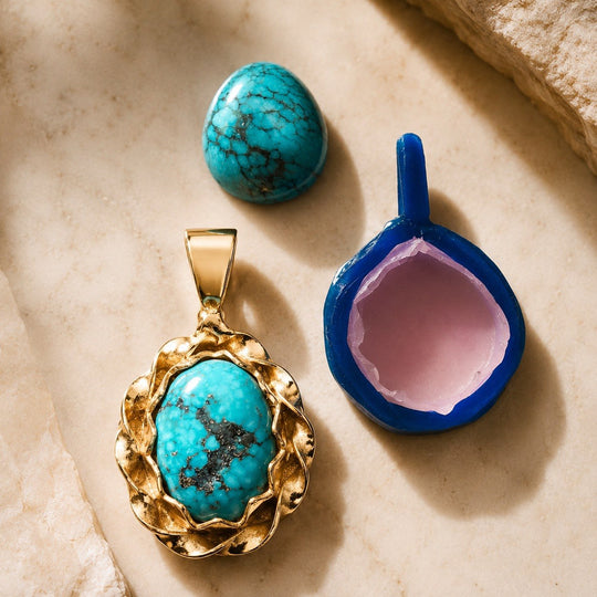 Craft & Cast jewelry workshop — turquoise cabochon, finished gold pendant, and lost-wax casting model on natural stone