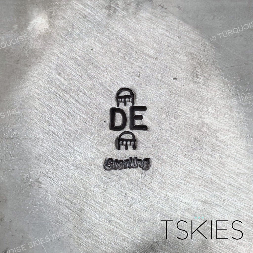 Documented sterling silver hallmark of Devin Edison, Diné silversmith — Native American maker's mark: initials DE between two small figural stamps, Sterling below