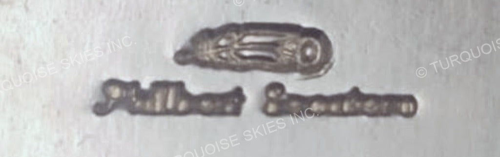 The hallmark of Philbert Secatero, Navajo silversmith - a feather stamp struck above his cursive name stamp, photographed at T.Skies